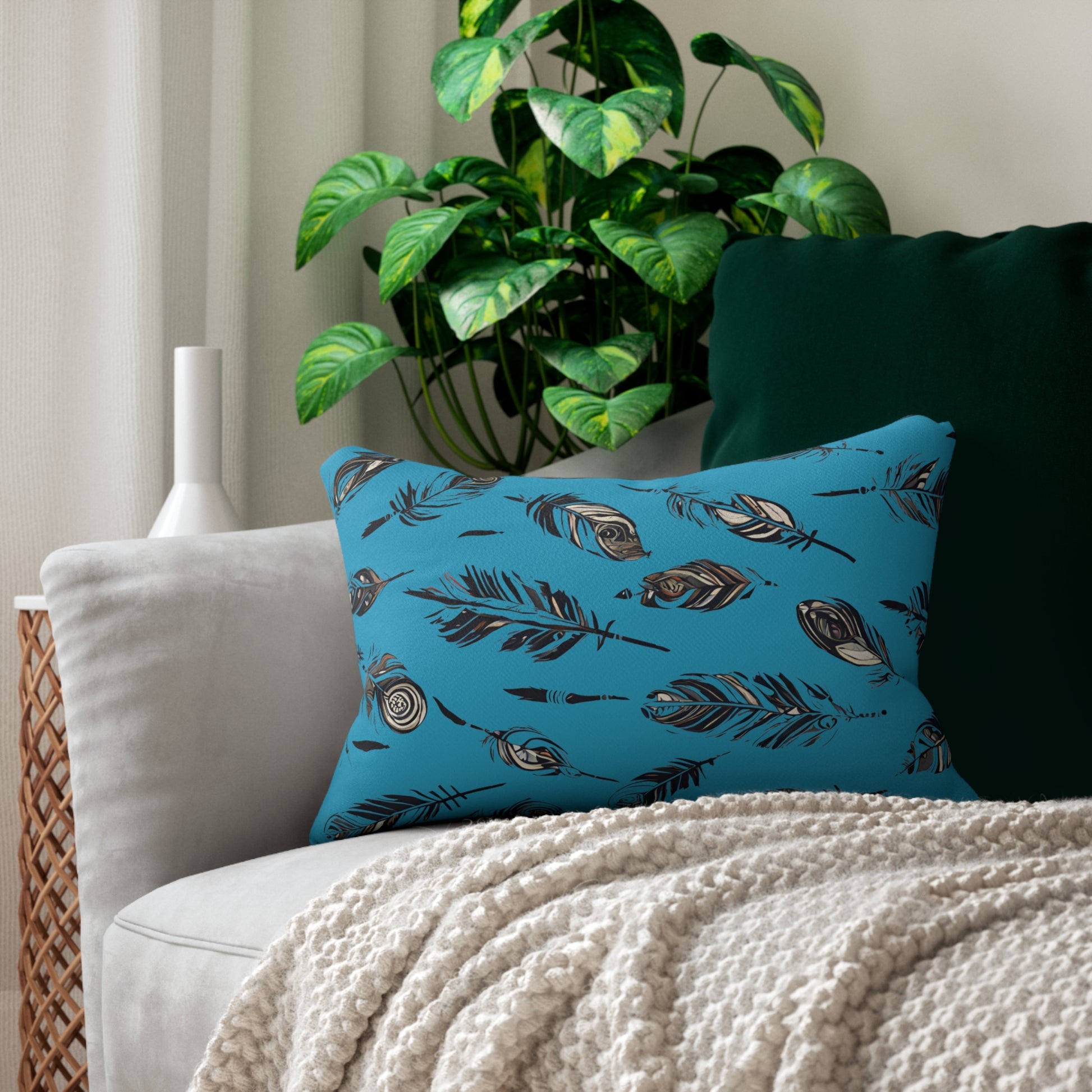 Inviting Rectangular Native American Turquoise Feather-Design Pillow Accentuating a Grey Sofa, Enhanced by a Stylish Green Plant in a Floor Vase and Softened by White Curtains in the Background.